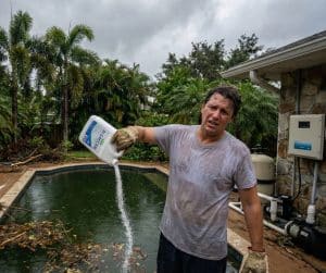 Worrided man adding chemicals to the pool